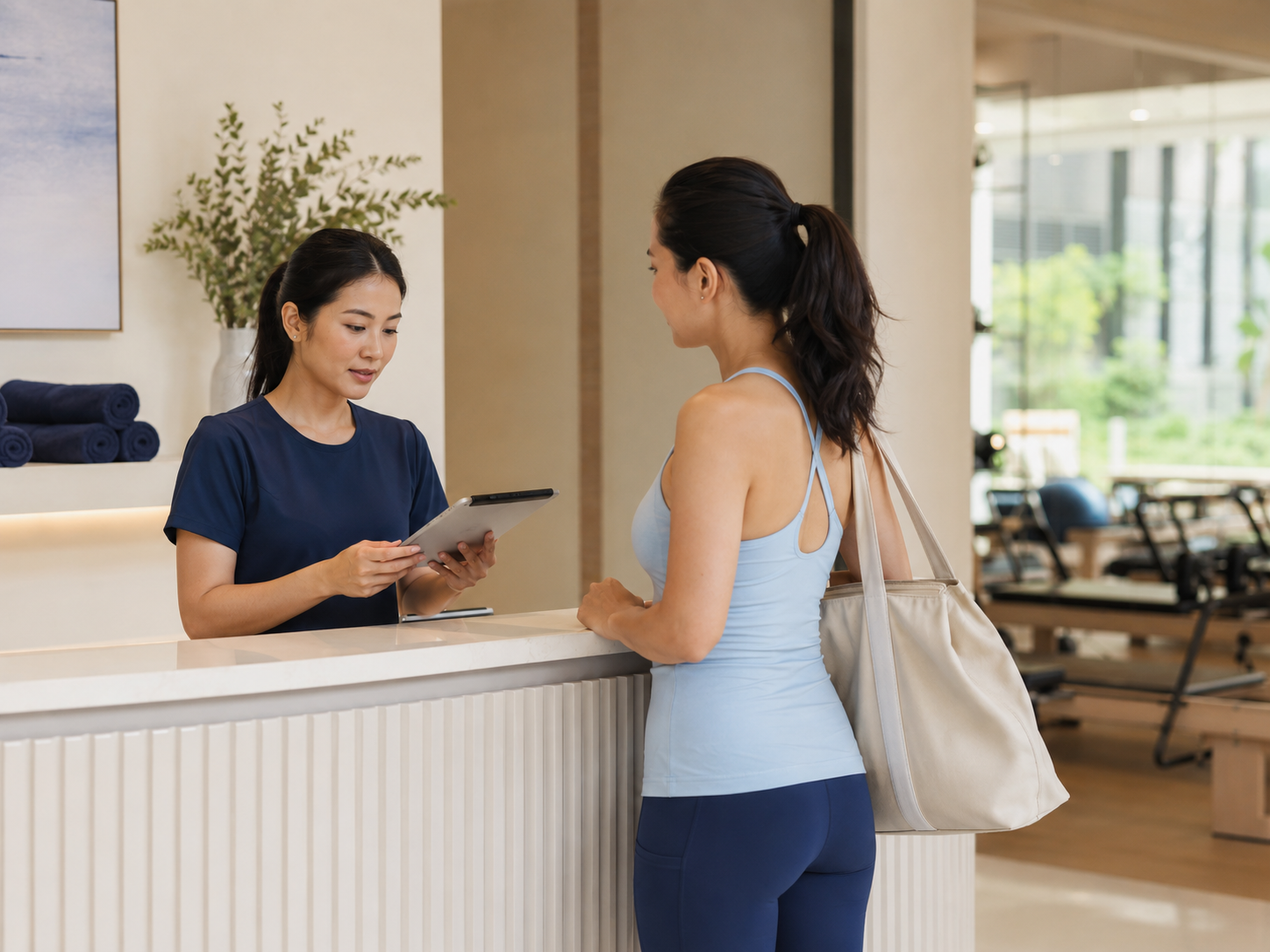 Studio receptionist assisting a customer with a tablet at the front desk